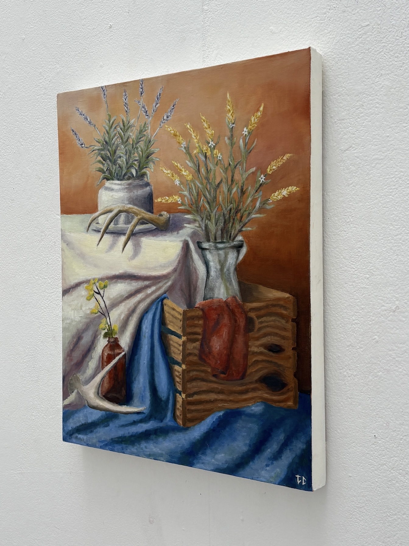 Oil painting still life with flowers, antlers, fabric, and a wooden box detail view