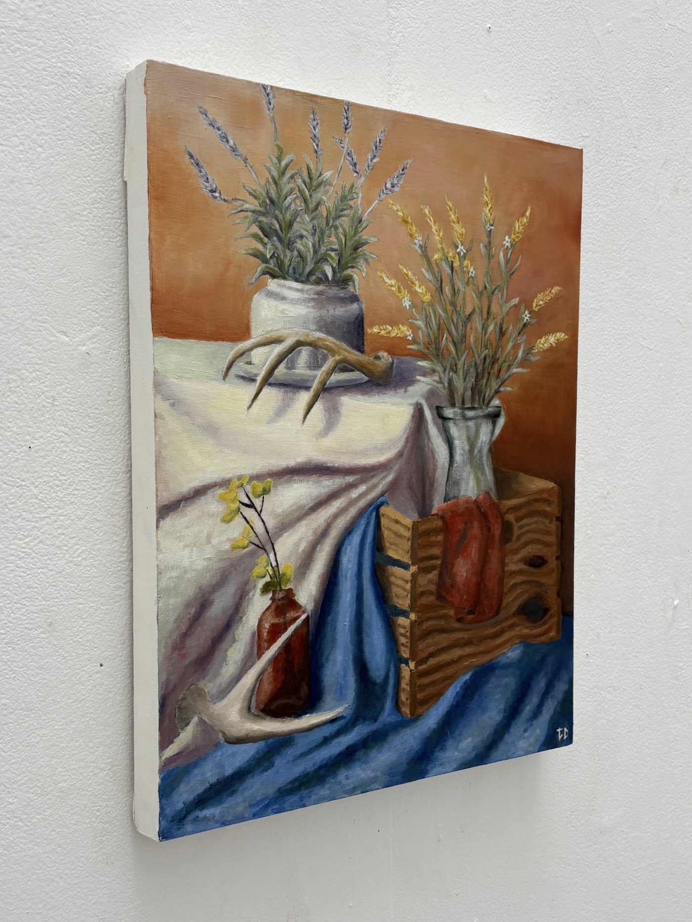 Oil painting still life with flowers, antlers, fabric, and a wooden box detail view